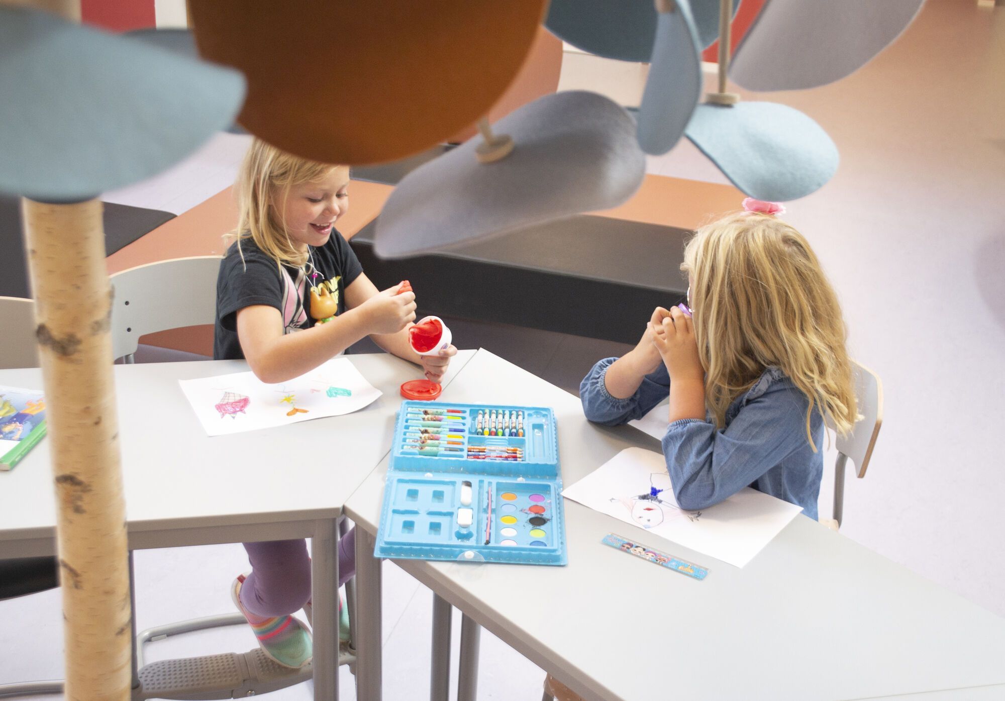 Leerlingen aan tafel onder Leaf Lamps in een school