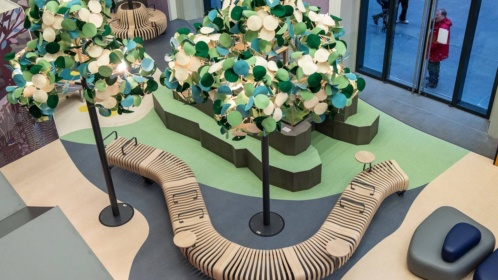 Modulaire zitbanken van Green Furniture Concept rond beplante eilanden met Leaf Lamp-verlichting in een publieke hal